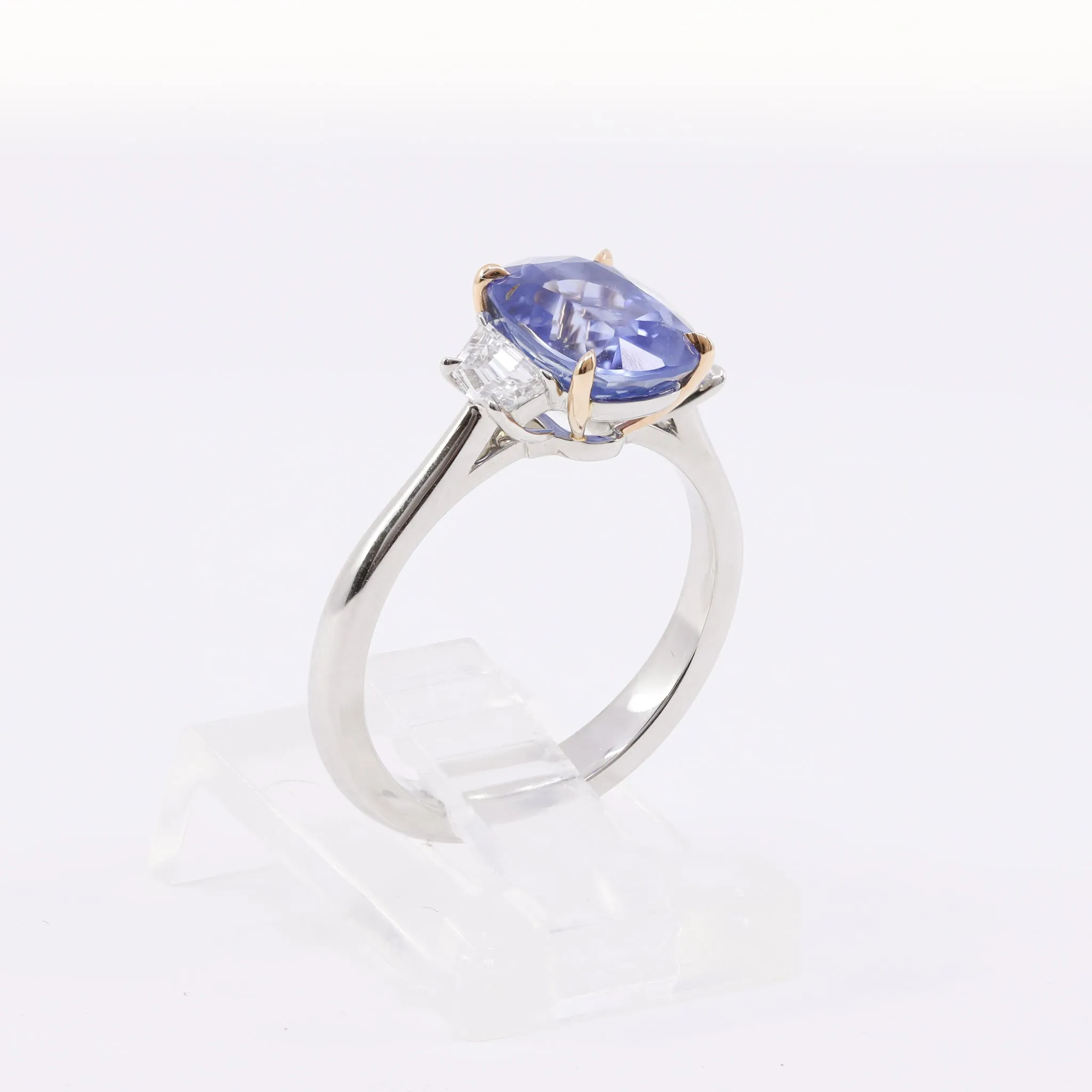 PLATINUM AND 18K ROSE GOLD THREE-STONE RING WITH A CUSHION BLUE SAPPHIRE AND CADILLAC STEP-CUT SIDE DIAMONDS 0.43CTW